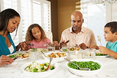 Family of four enjoying meal at home together