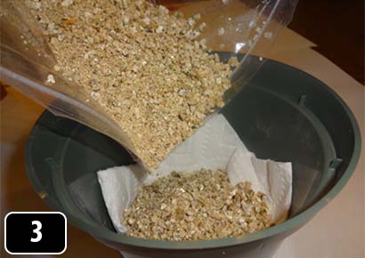 Vermiculite being poured onto a folded paper towel in plastic pot.